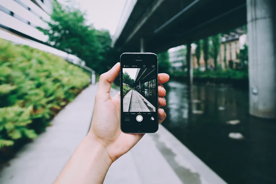Una mano sostiene un teléfono móvil encuadrando una fotografía en una calle