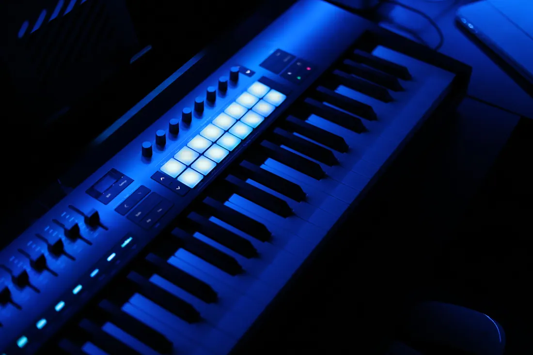 Teclado controlador MIDI iluminado en azul con pads y mandos