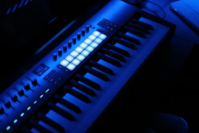 Teclado controlador MIDI iluminado en azul con pads y mandos