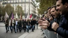 Un grupo de personas aplaude a manifestantes con banderas en una calle parisina