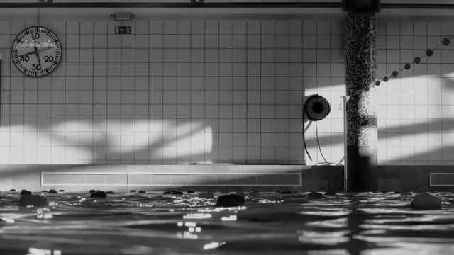Piscina cubierta con un reloj de pared y una columna de mosaico