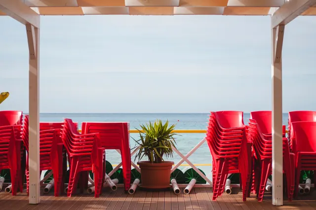 Sillas rojas apiladas en una terraza frente al mar