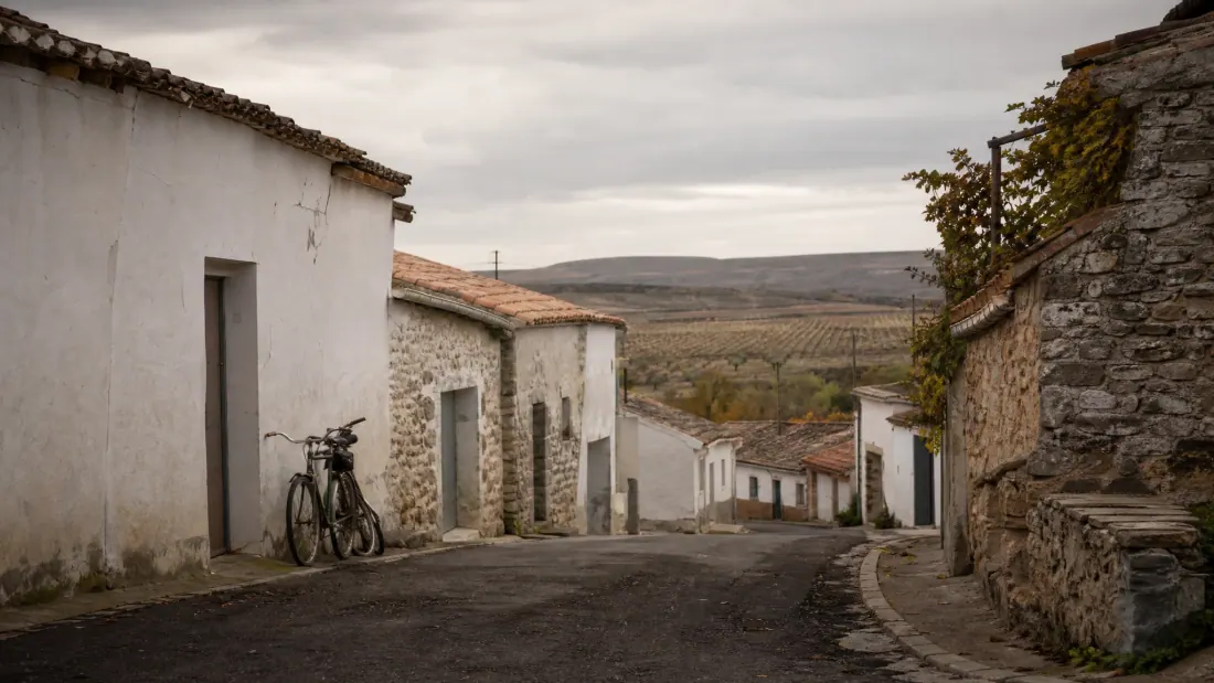 Calle de un pueblo rural con casas de piedra y una bicicleta apoyada en la fachada