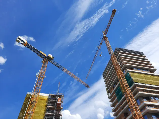 Grúas de construcción junto a un edificio en obras