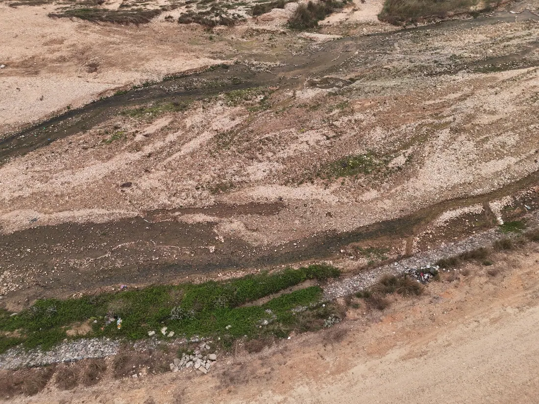 Vista aérea de un cauce seco con escombros y vegetación dispersa