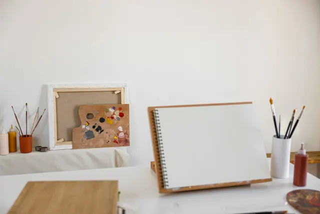 Material de pintura y un cuaderno de dibujo sobre una mesa