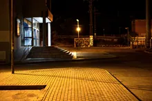 Calle nocturna con escaleras y farola junto a un edificio con grafitis