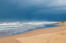 Playa con oleaje bajo un cielo tormentoso