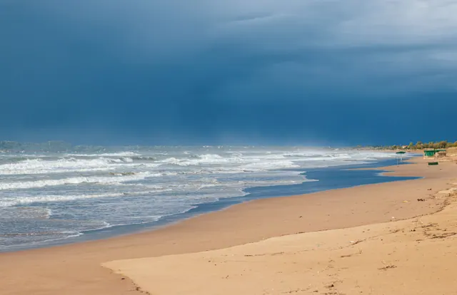 Playa con oleaje bajo un cielo tormentoso