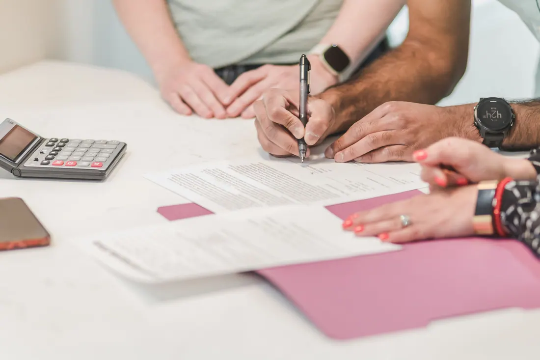 Varias personas firman documentos sobre una mesa