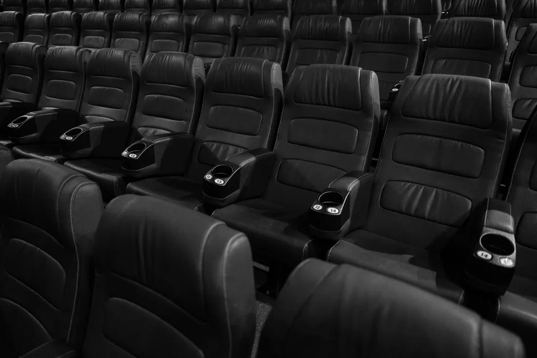 Filas de butacas de cuero vacías en una sala de cine