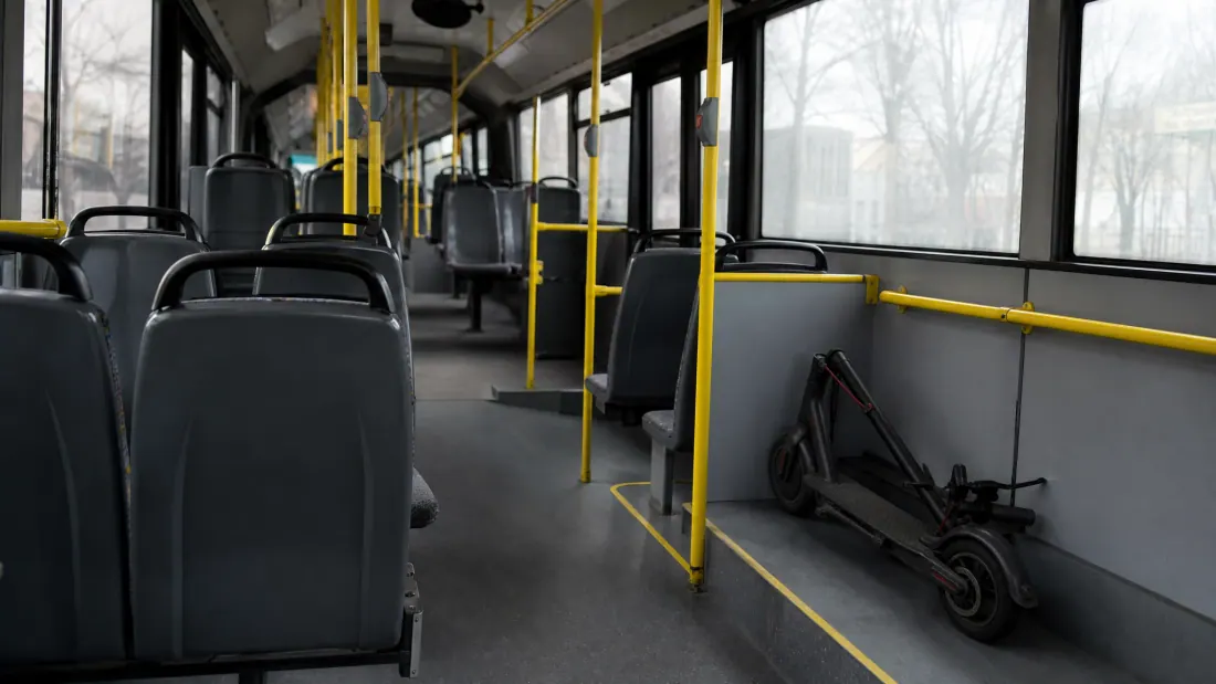 Interior de autobús urbano con asientos vacíos y un patinete eléctrico aparcado