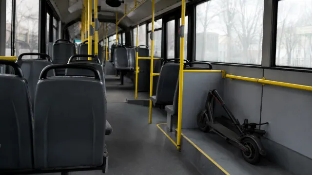Interior de autobús urbano con asientos vacíos y un patinete eléctrico aparcado