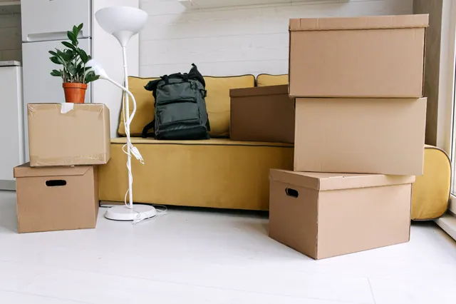 Cajas de mudanza apiladas junto a un sofá en un salón