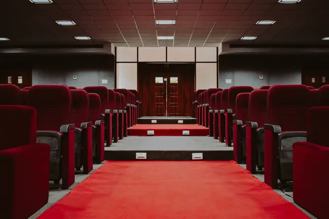 Interior de un auditorio vacío con butacas rojas y pasillo central