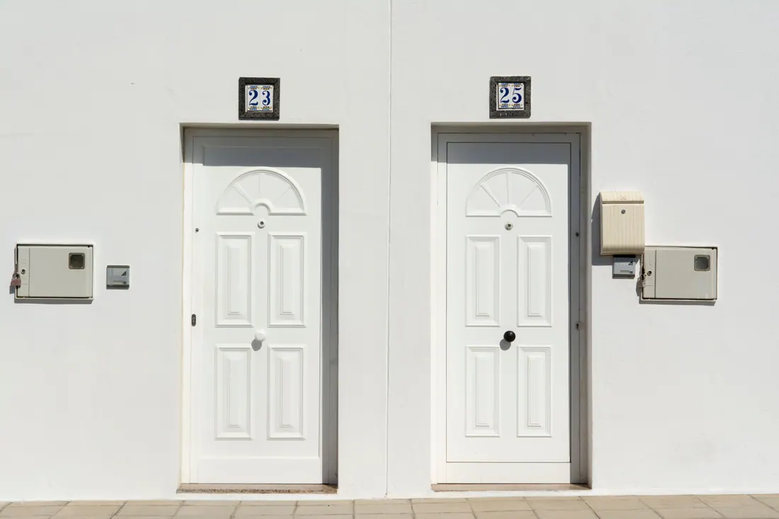 Dos puertas blancas con números 23 y 25 en una fachada