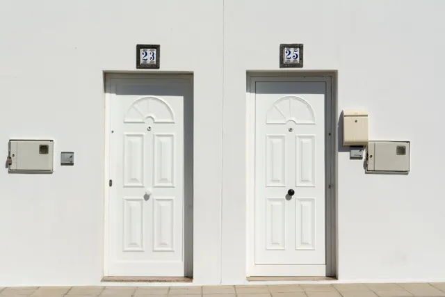 Dos puertas blancas con números 23 y 25 en una fachada