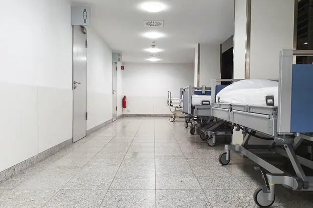 Pasillo de hospital con camillas alineadas junto a la pared