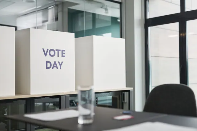 Urna de votación y sobres sobre una mesa
