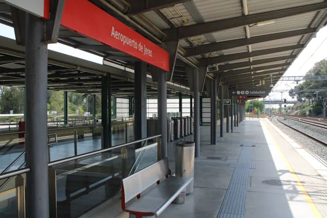 Andén de una estación de tren con viajeros esperando la llegada de un convoy