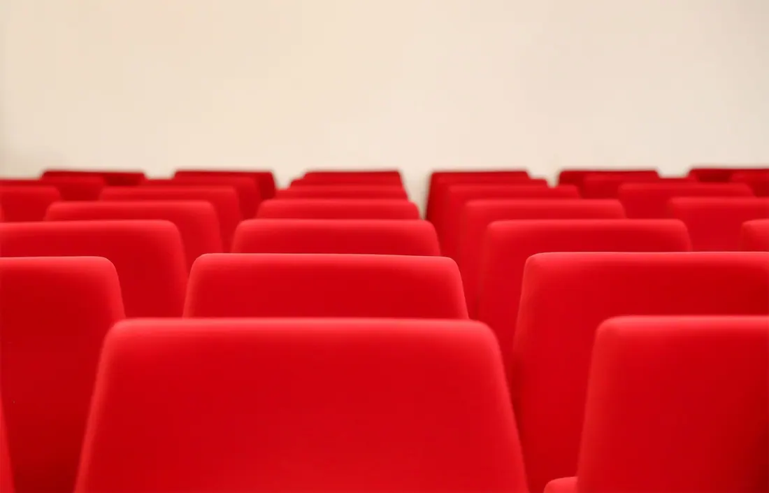 Filas de butacas rojas vacías en una sala de proyección o auditorio