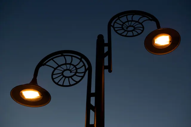 Farola con diseño de espiral encendida al anochecer