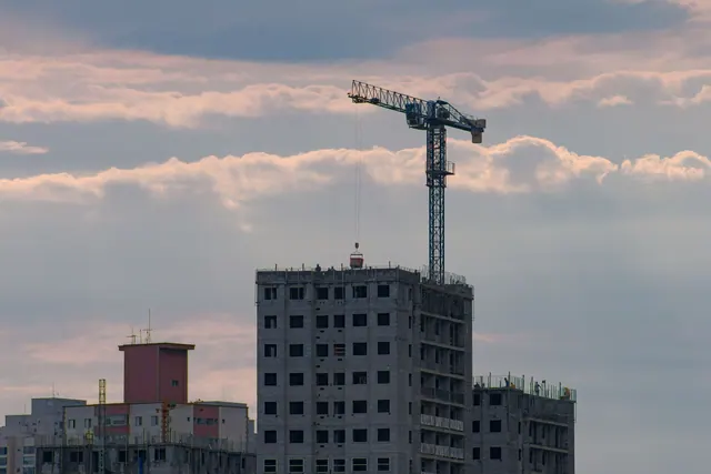Grúa de construcción sobre un edificio en obras al atardecer