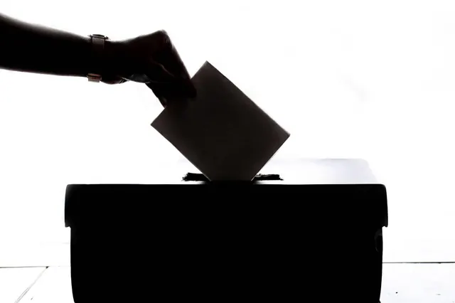 Una mano introduce una papeleta en una urna electoral