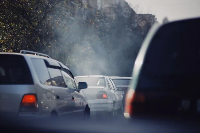 Coches atascados en una calle con humo de tubos de escape