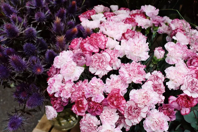 Puesto de flores con cubos de claveles y ramos en un mercado