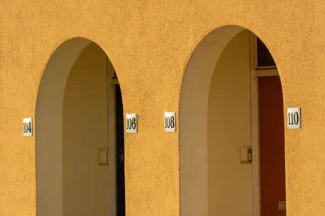 Puertas numeradas bajo arcos en una fachada de apartamentos