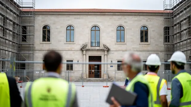 Varios trabajadores con arneses de seguridad observan un edificio histórico