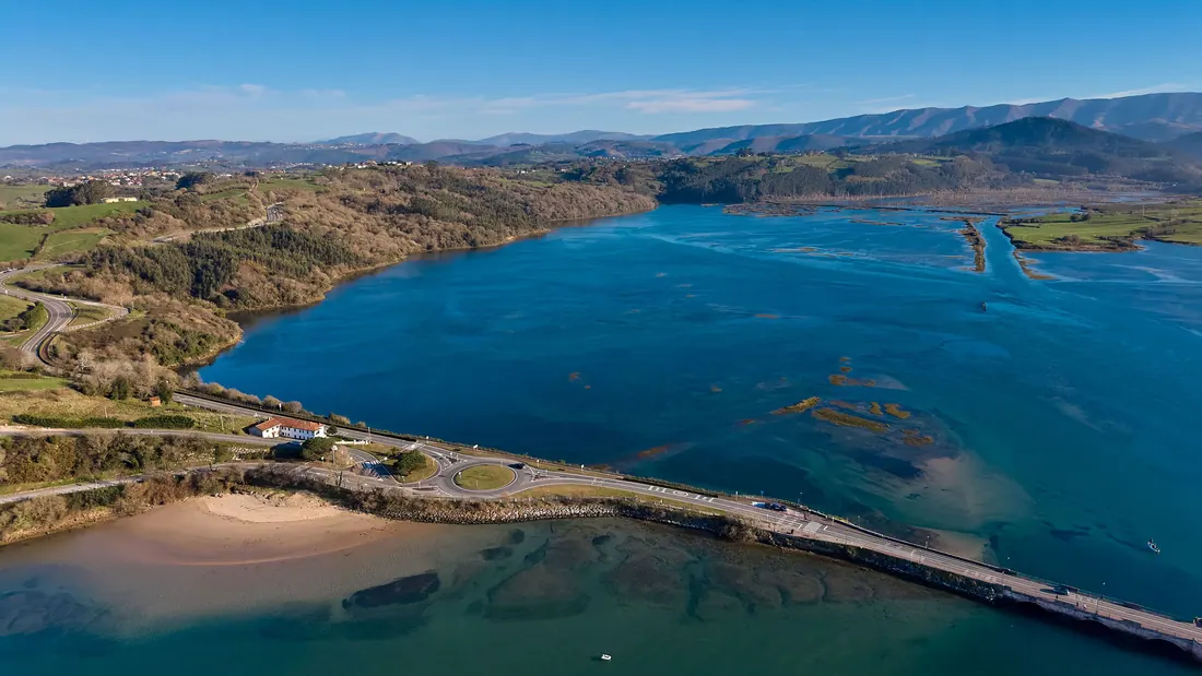 Vista de una ría con villas y prados verdes en la costa del norte peninsular