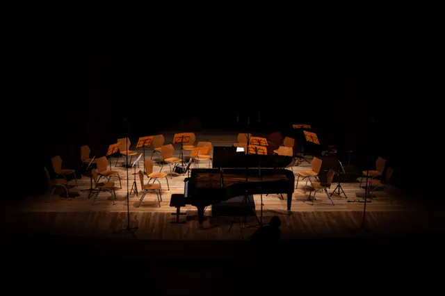 Escenario vacío con sillas, atriles y un piano de cola antes de un concierto