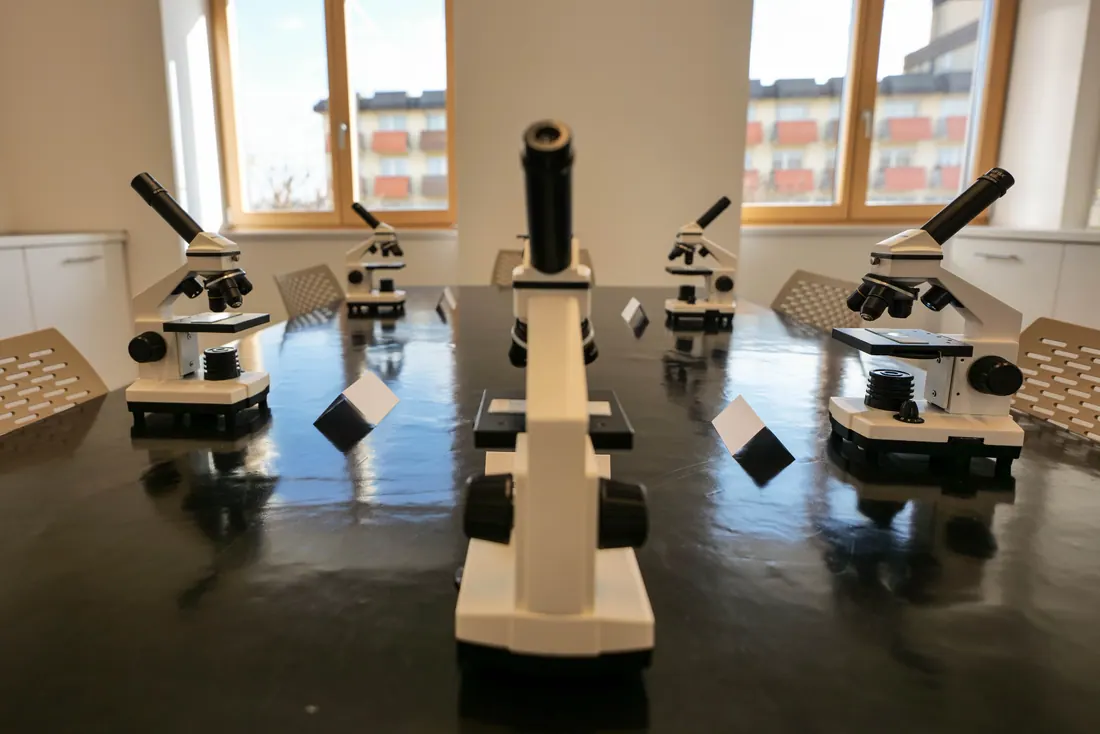 Varios microscopios dispuestos sobre una mesa en un aula