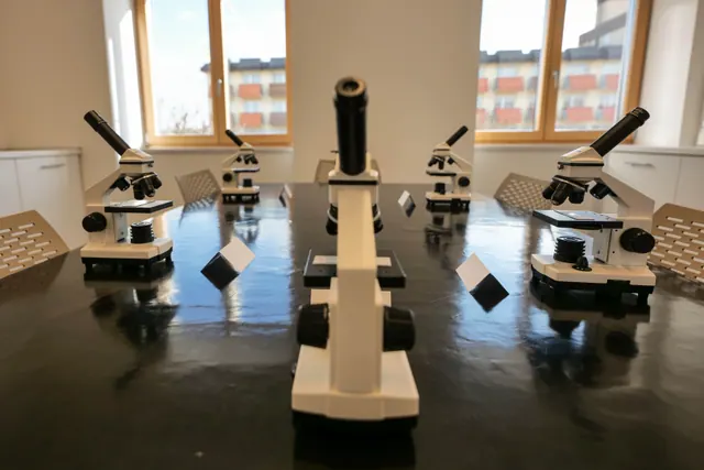 Varios microscopios dispuestos sobre una mesa en un aula