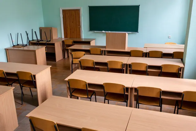 Un aula vacía con mesas, sillas y una pizarra