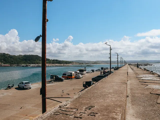 Vehículos aparcados junto a un espigón de piedra junto al mar