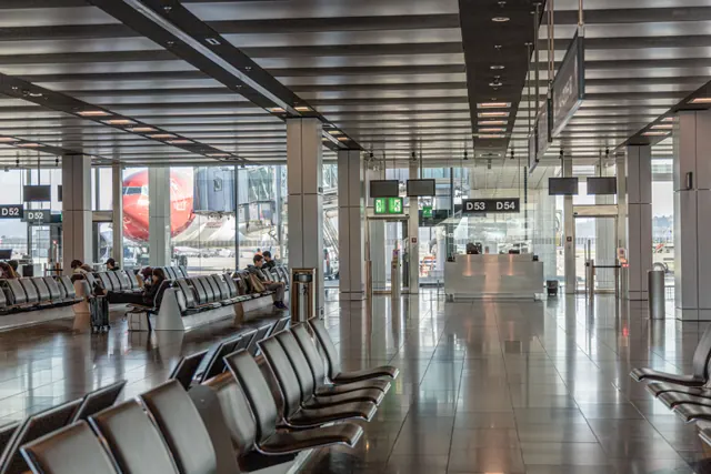 Sala de espera de un aeropuerto con vista a un avión en la pista