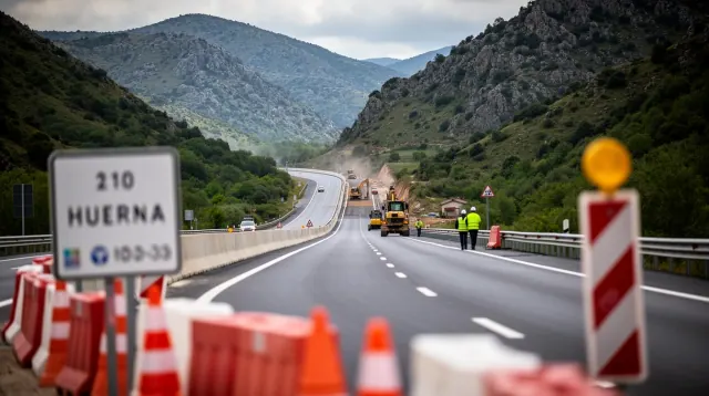 Obras de mantenimiento en una autopista de montaña con señalización y vehículos