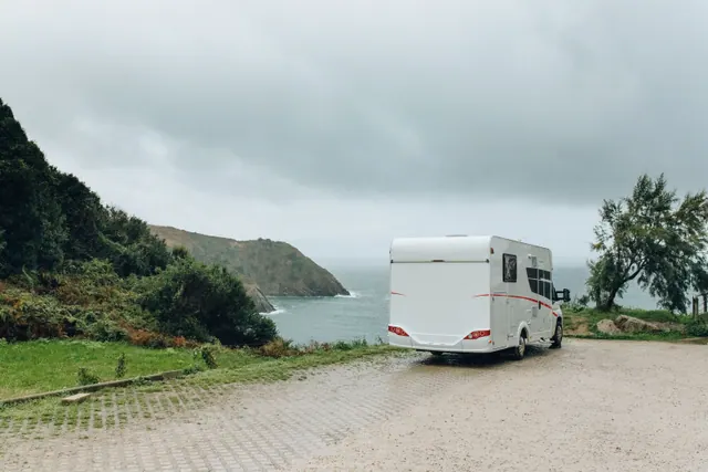 Autocaravana estacionada frente a un acantilado junto al mar