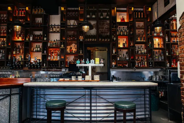 Barra de un bar con estanterías repletas de botellas