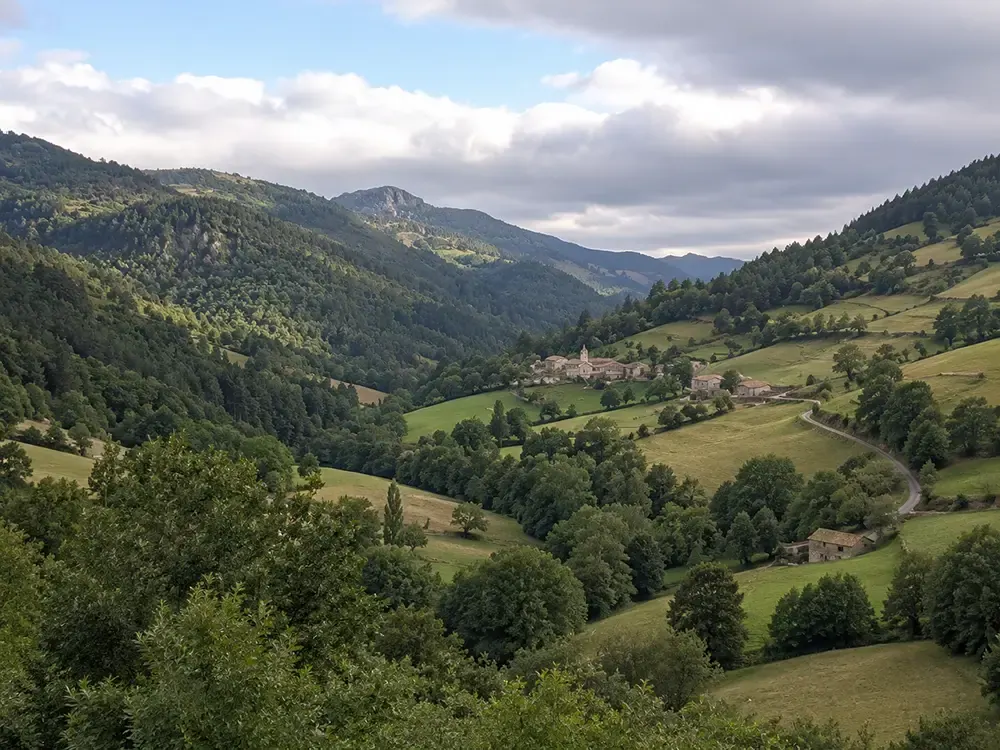 Valle con prados, bosque y aldeas dispersas entre montañas