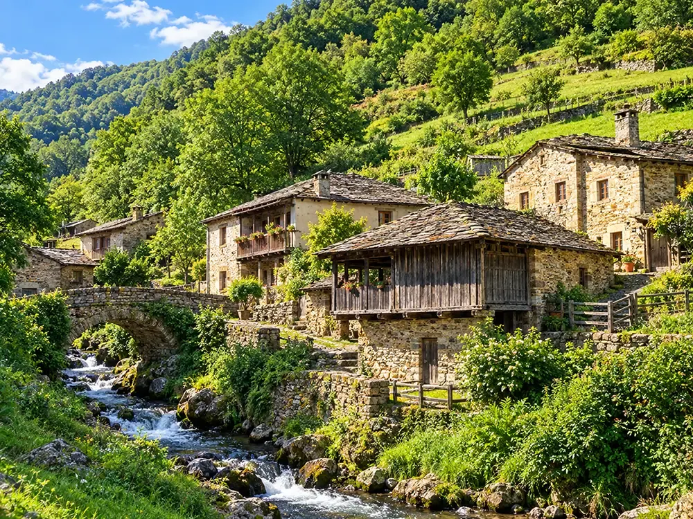 Casas de piedra y un hórreo junto a un riachuelo, con la ladera boscosa al fondo