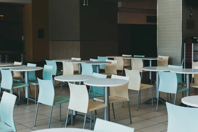 Mesas redondas y sillas de colores vacías en el comedor de un centro escolar