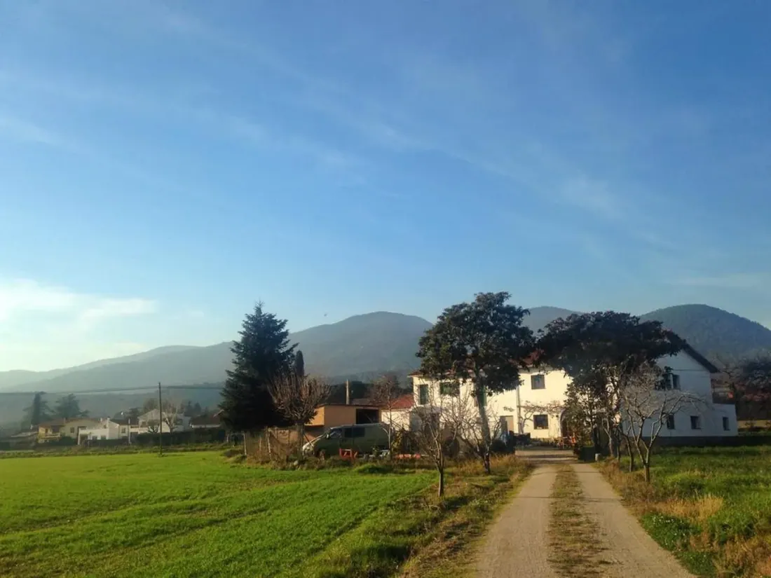 Una masía rodeada de prados y montañas al fondo