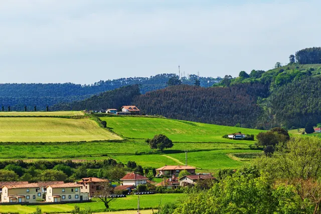 Paisaje rural verde con casas dispersas entre colinas