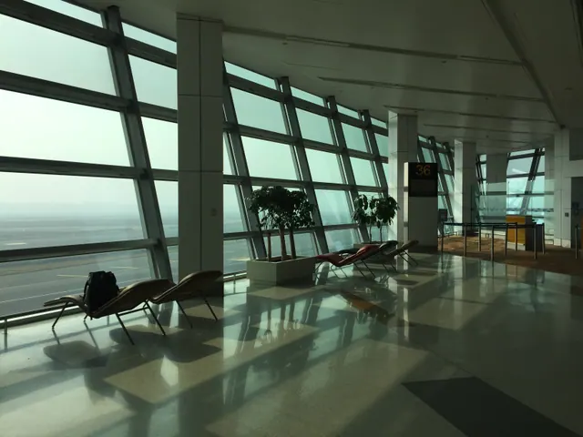 Sala de espera vacía junto a grandes ventanales en una terminal aérea