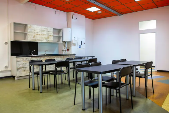 Comedor con mesas, sillas y una pequeña cocina