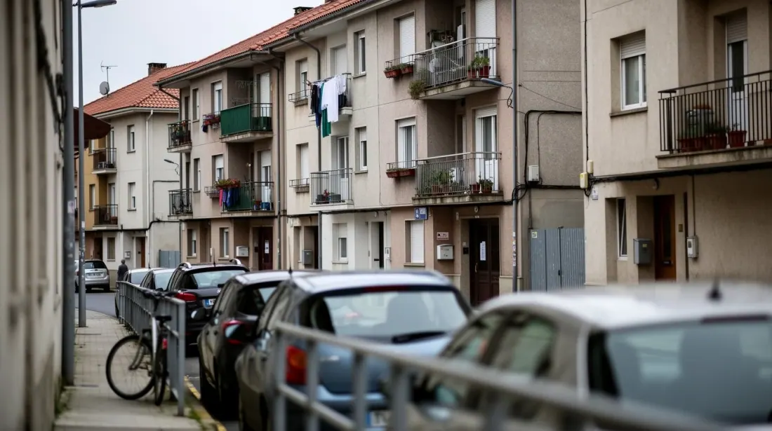 Calle de un barrio residencial con edificios de viviendas y vehículos estacionados